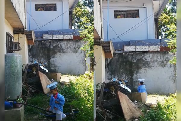 Batang babae, tumayo sa labas ng kulungan ng ina para ipakita ang suot na toga